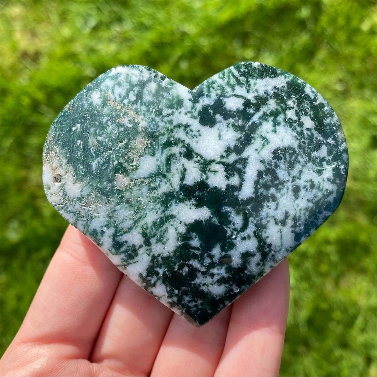 mineral con detalles verdes y blancos con forma de corazon y con cristales drusa